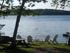 Adirondack chairs and picnic table by the water
