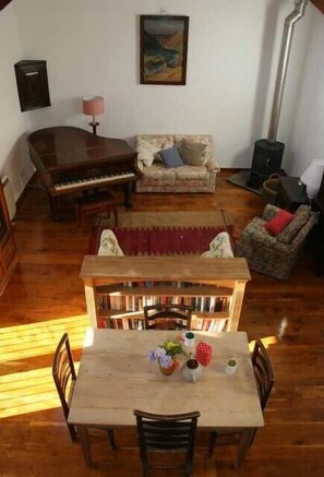 Open plan living area with grand piano and woodburning stove