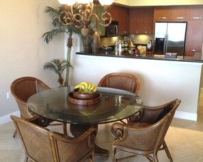 Informal dining area with bamboo chandelier and seats around glass table