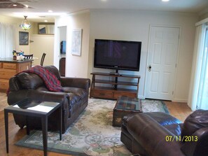 Living room with large flat screen tv, patio out the door on the right. 