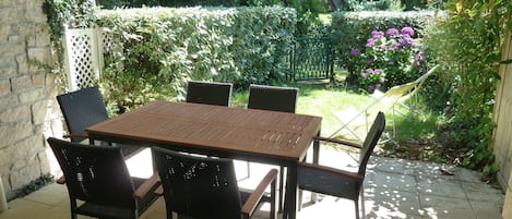 La grande terrasse couverte avec le petit jardin clôturé.