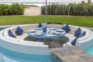 An outdoor eating area surrounded by the pool is steps away from the beach