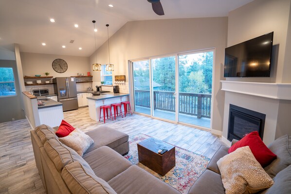 Open floor living room and kitchen space with lofted ceilings.