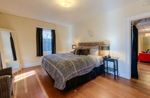 Queen bed in spacious bedroom with wood flooring