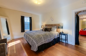 Queen bed in spacious bedroom with wood flooring