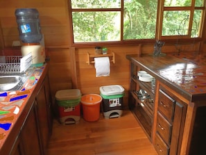 View of kitchen with essential dishware, recycling, garbage & compost bin!