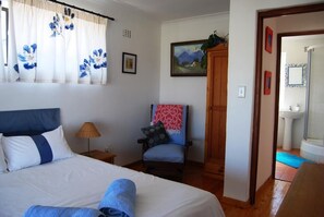 Main bedroom with balcony, ceiling fan and queen bed. 