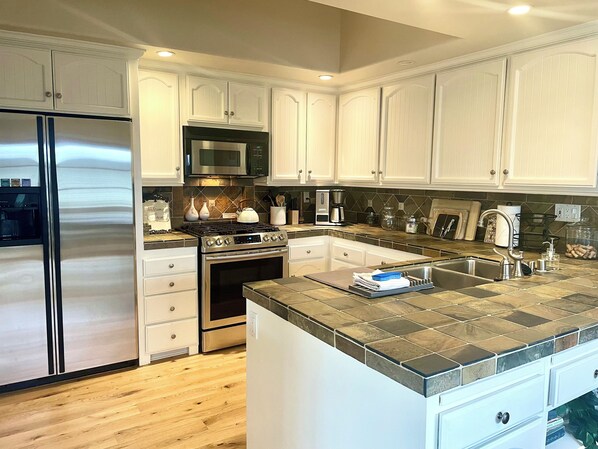 French country inspired kitchen with slate countertops and stainless appliances