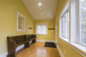 vaulted rear sunroom with bistro table and 4 chairs, 2 coat hooks  and a bench