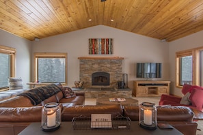 Living room with plenty of cozy seating, wood-burning fireplace and 55" TV. 