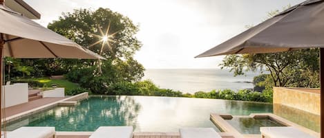 Oceanfront pool with comfortable lounge chairs and shaded umbrellas