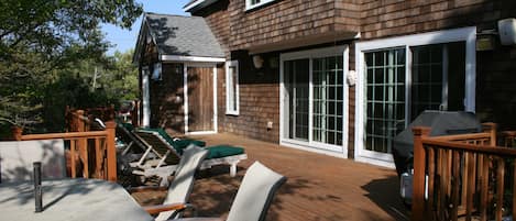 Back deck of house, with outdoor shower in background. Dining area on left