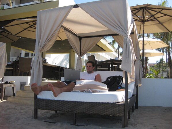 My son enjoying his canopy bed on the beach with Jorge his awesome waiter!!!