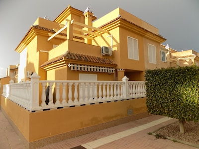 Casa adosada de tres dormitorios, dos baños, piscina comunitaria, wifi, aire acondicionado y televisión vía satélite.