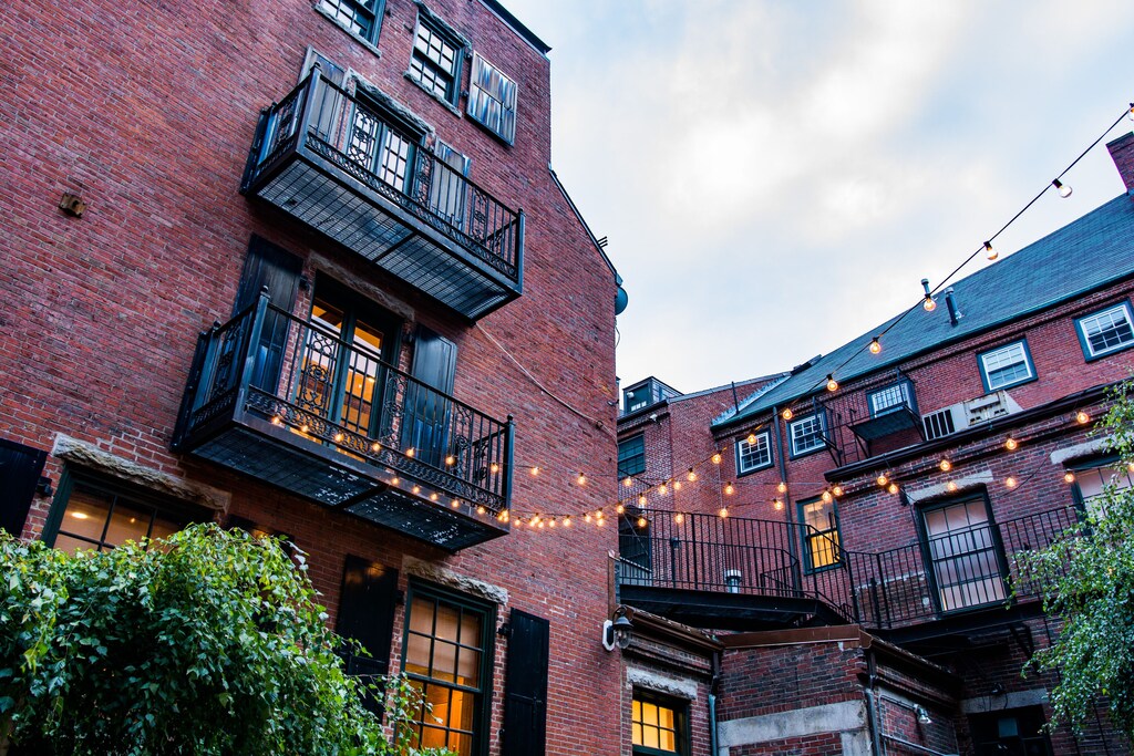 Red brick historic buildings with black iron balconies and outdoor lights decorating the courtyard