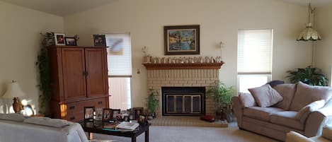 Open, bright living room with gas fireplace and television.