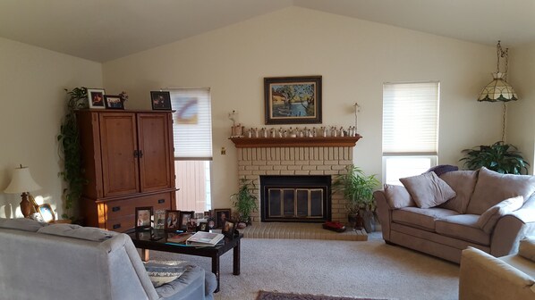 Open, bright living room with gas fireplace and television.