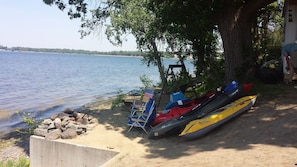 Campfire on elevated sandy beach with swing and water toys.