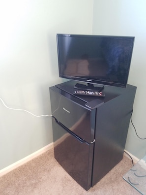 Fridge with freezer in the room. TV has streaming apps programmed in.