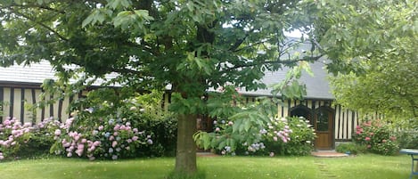 façade à colombage et hortensias  d'un côté et briques et silex de l'autre côté.