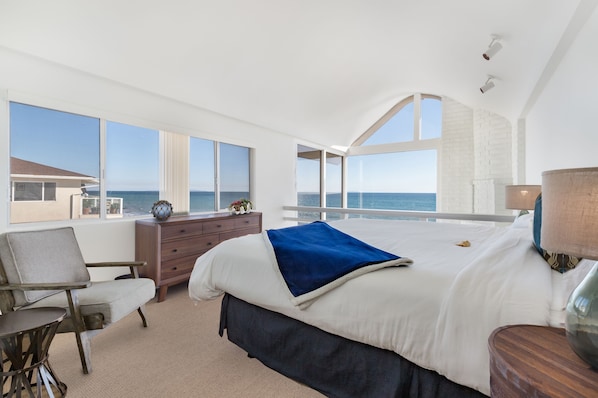 Primary bedroom has panoramic oceanfront views, vaulted ceiling & en-suite bath
