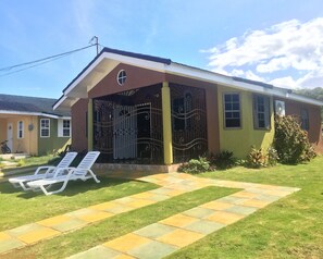 Veranda with table and chairs, plus open yard space with lounge chairs