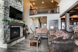 Comfortable living room with huge flat screen tv opens up to kitchen area