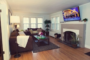 Living room w/ 60" HDTV and wood-burning fireplace