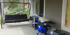 3 person swing, barbecue, cooler and small fountain, recycling bin.
