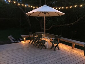 Nicely lighted deck with large dining table and lower brick patio.