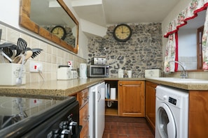 Kitchen with exposed flint and stone wall.