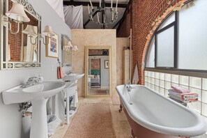 Light-filled Master Bath with soaking tub and shower located beyond the mirror