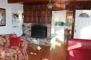 Veranda living room with wood burning fire place looking into kitchen.