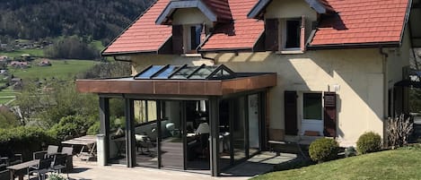 maison avec véranda et terrasse vue du jardin 