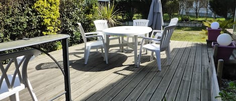 Terrasse bois devant véranda dans le jardin avec plancha