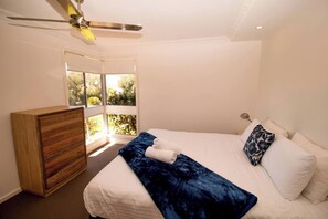 Unwind in the serene first bedroom, complete with a king-sized bed, garden views and ceiling fan for a restful night’s sleep.
