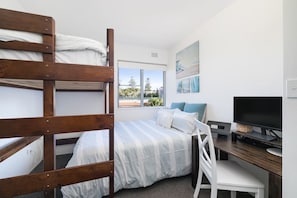 Bedroom with queen bed, king single loft bed, desk with monitor and laptop stand