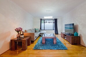 Unwind in the airy main living space with timber floors, cosy sofas, a gas fireplace, and reverse cycle air con—perfect for year-round comfort.