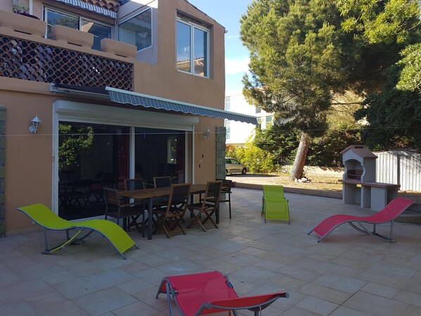 Une grande terrasse avec son barbecue et sa table d'extérieur