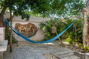 Private patio under the trees, featuring hammocks,  grill and dining table.