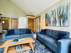 Living room with access to the deck, dining area and kitchen with vaulted ceilings