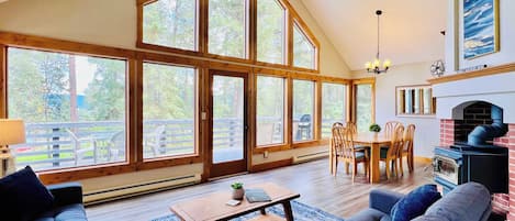 Living room with access to the deck, dining area and kitchen with vaulted ceilings