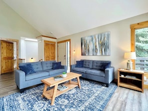 Living room with access to the deck, dining area and kitchen with vaulted ceilings