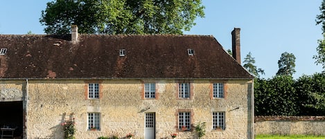 The outside of the farmhouse, in an enclosed space featuring a small orchard.