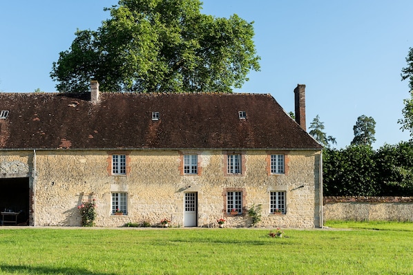The outside of the farmhouse, in an enclosed space featuring a small orchard.