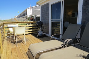 on the deck is a gas grill, 2 lounge chairs, and a table with chairs.