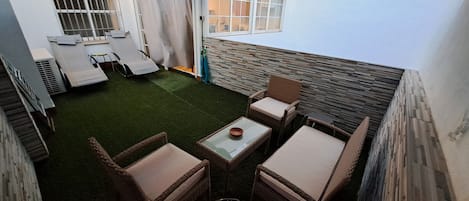 Terraza, con mesa, sillones, hamacas, luces solares, césped artificial, manguera