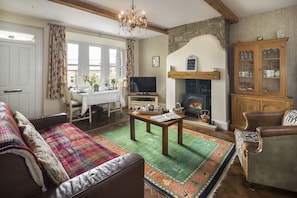 A spacious room with high beamed ceilings, and a gas wood burner 