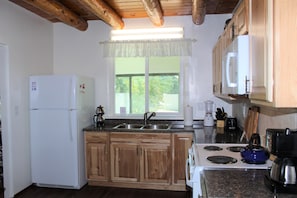 Kitchen has plenty of cookware/dishes.  Refrigerator/freezer, double sink
