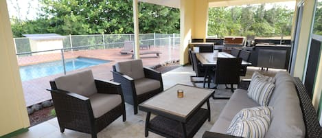 Large covered lanai with outdoor kitchen and dining - lap pool in the background